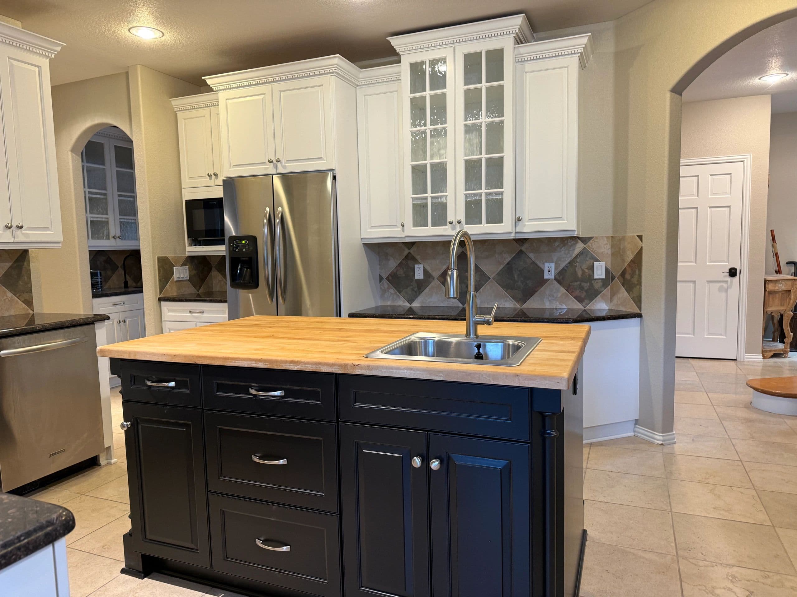 Kitchen with white painted upper cabinets and a navy island