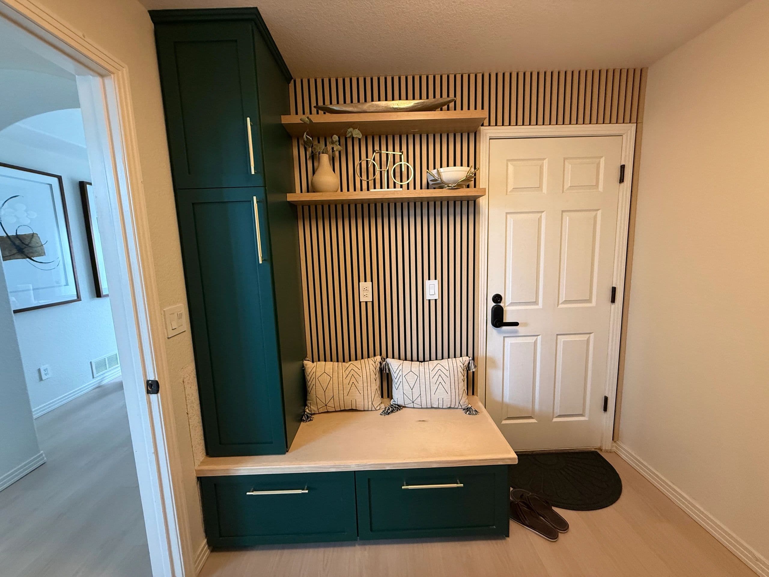 Emerald green mudroom built-ins with a bench and gold pulls
